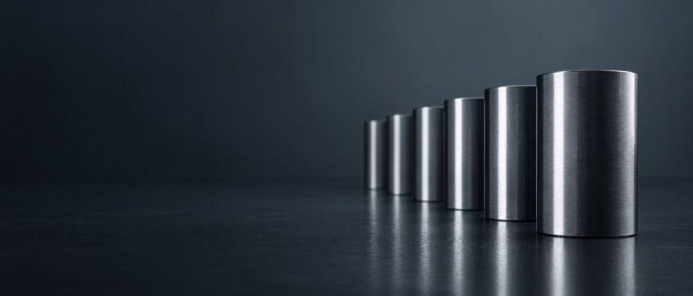 Una fila de cilindros de acero cepillado en perspectiva, sobre una superficie oscura.